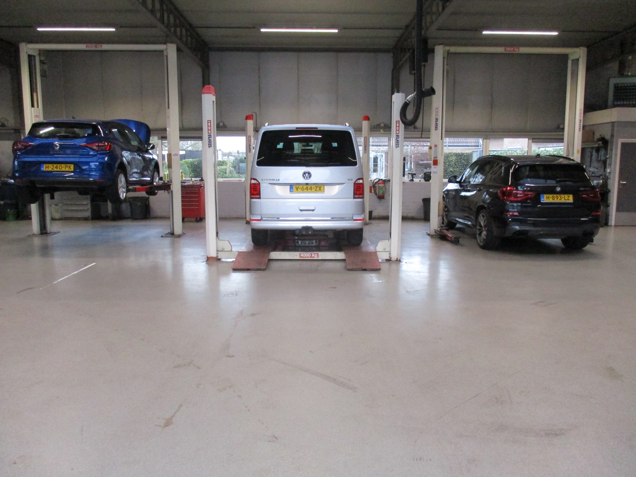 De werkplaats van Garage Grinwis met drie hefbruggen en auto's erop